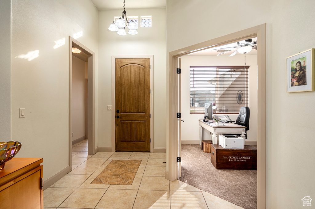 Entrance foyer featuring ceiling fan with notable chandelier, light tile patterned floors, and a wealth of natural light