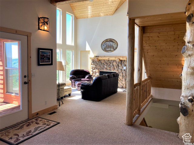 Carpeted living room with wood ceiling, high vaulted ceiling, plenty of natural light, and a fireplace