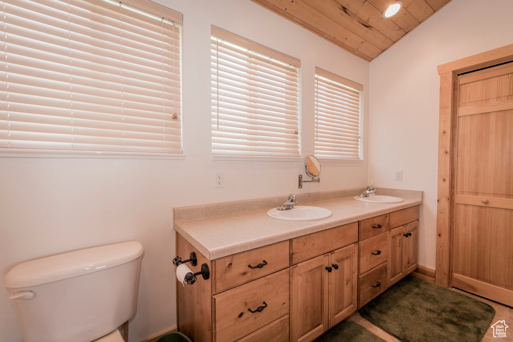 Bathroom featuring wood ceiling, vaulted ceiling, vanity, and toilet