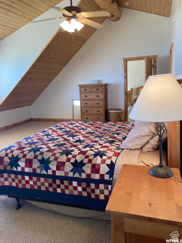 Bedroom featuring wooden ceiling, carpet, lofted ceiling with beams, and ceiling fan