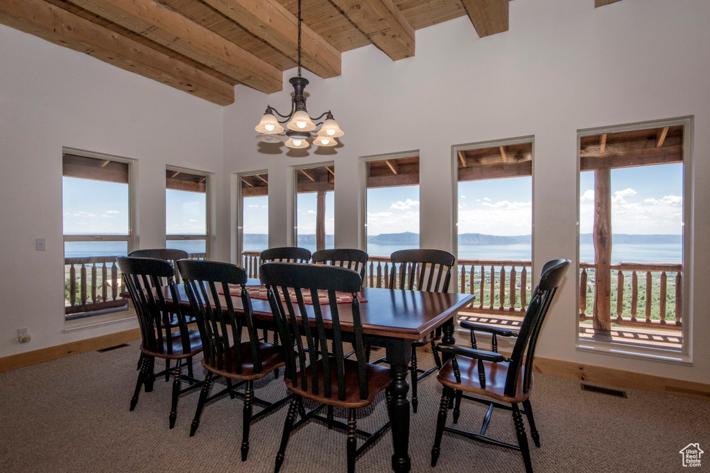 Carpeted dining space with wood ceiling, a water view, beamed ceiling, and a chandelier