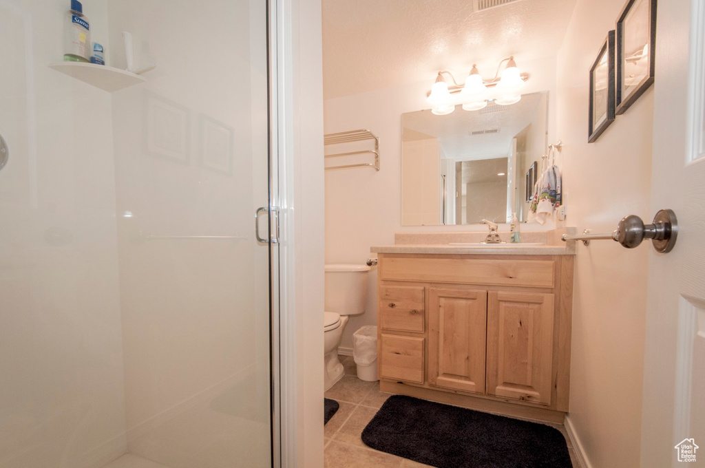 Bathroom featuring tile patterned floors, an enclosed shower, vanity, and toilet