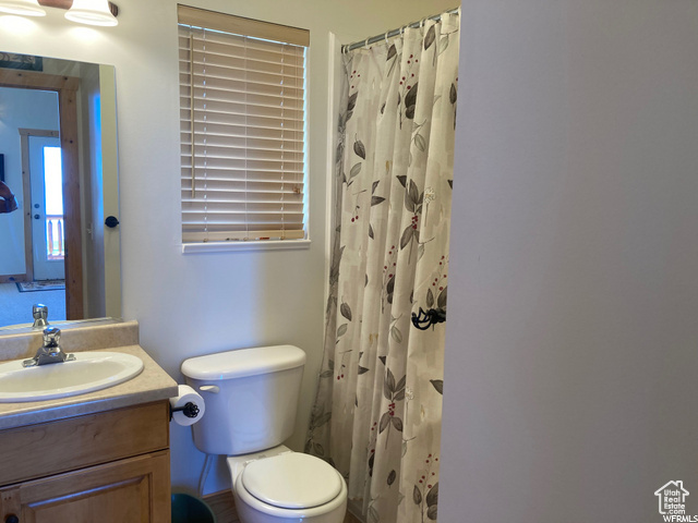 Bathroom with curtained shower, vanity, and toilet