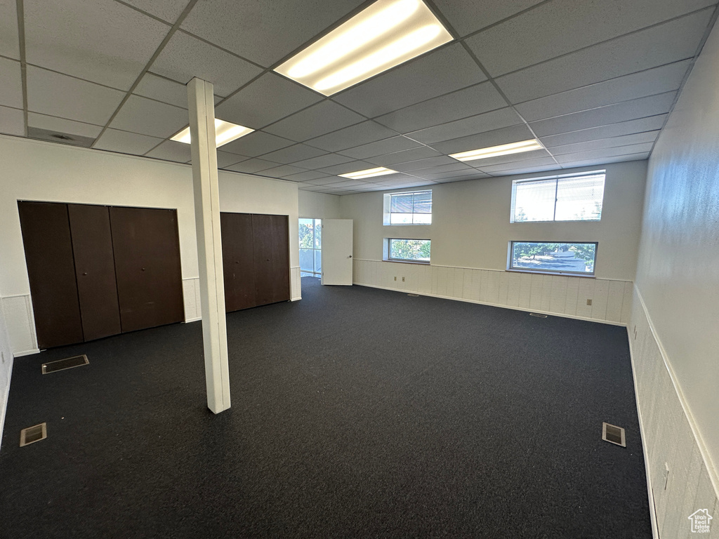 Basement featuring a paneled ceiling and dark carpet