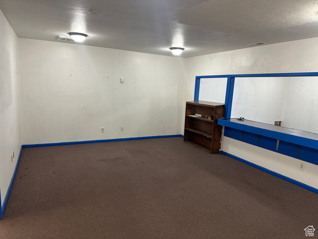 Empty room featuring a textured ceiling and carpet floors