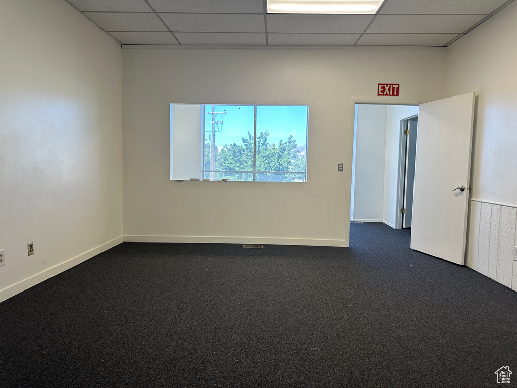 Unfurnished room with a paneled ceiling and dark colored carpet