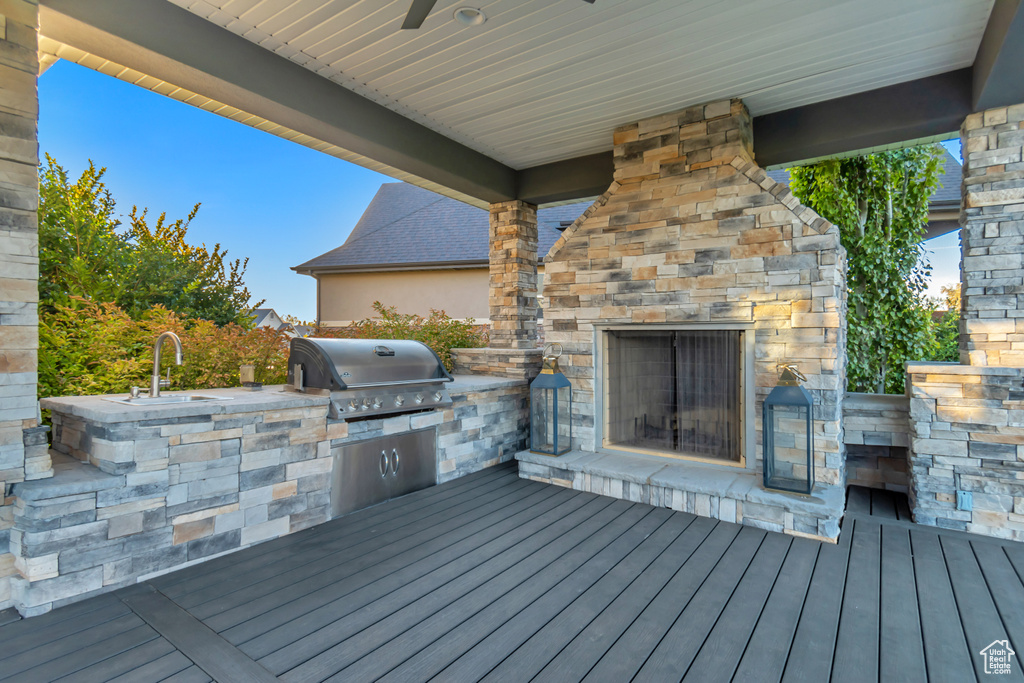 Deck with sink, an outdoor kitchen, a grill, and an outdoor stone fireplace