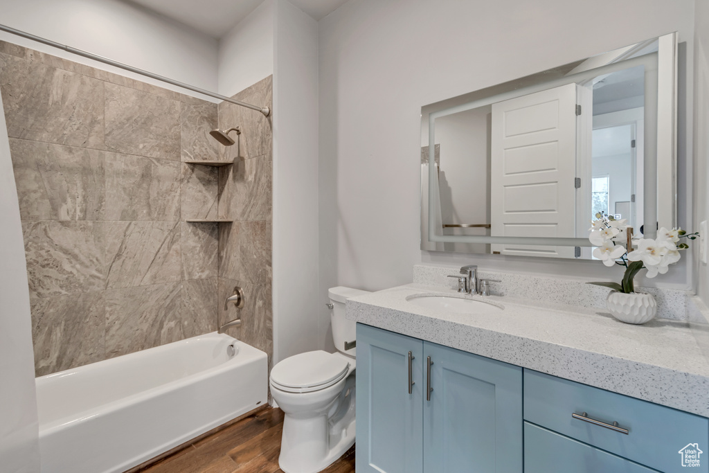 Full bathroom with hardwood / wood-style floors, toilet, vanity, and tiled shower / bath