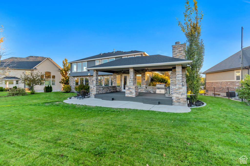 Back of property with cooling unit, a lawn, and a patio