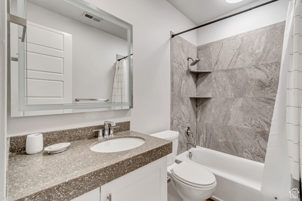 Full bathroom featuring vanity, toilet, and shower / tub combo with curtain