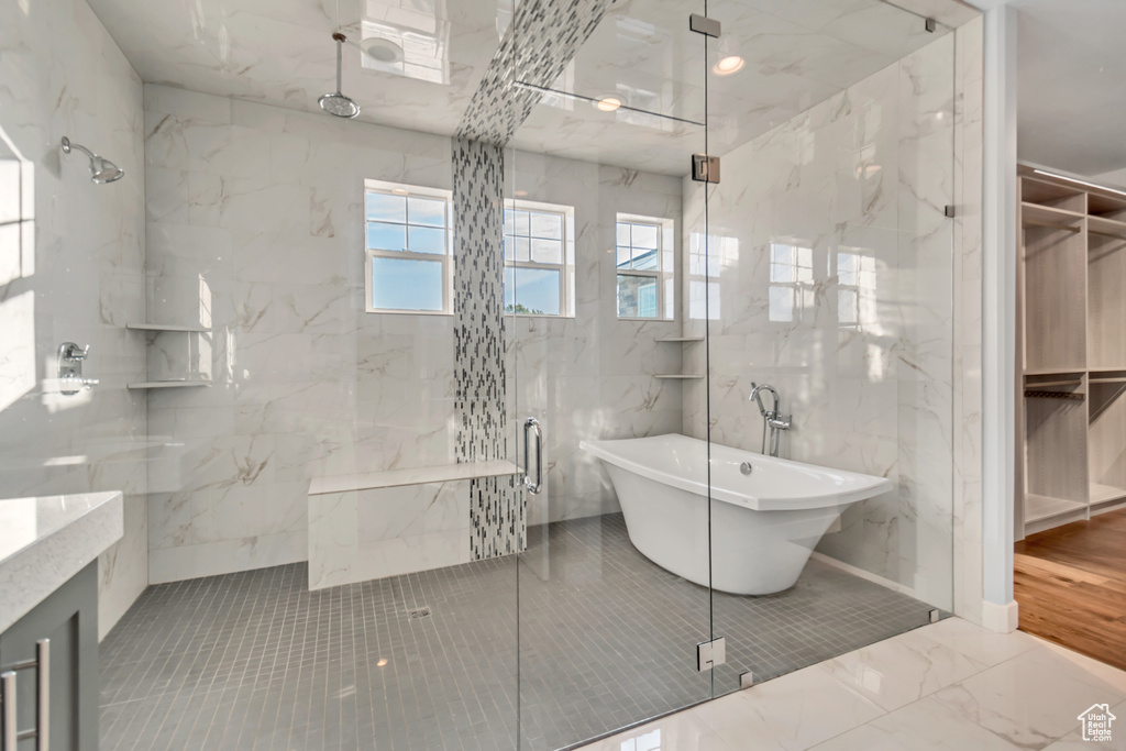 Bathroom with independent shower and bath, vanity, and tile walls