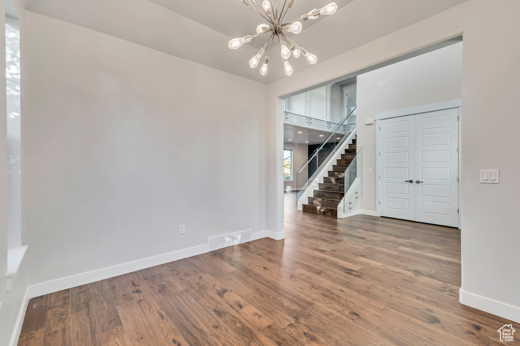 Empty room featuring a chandelier and wood-type flooring