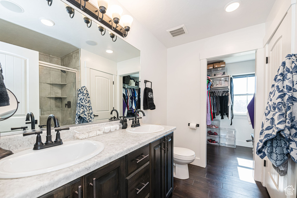 Bathroom featuring vanity, toilet, hardwood / wood-style floors, and a shower with door