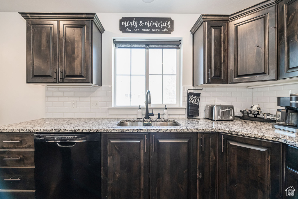 Kitchen featuring dark brown cabinetry, black dishwasher, backsplash, and sink