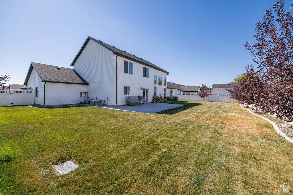 Rear view of property with a yard, central AC unit, and a patio area