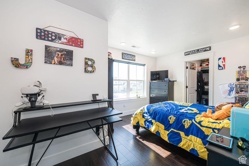 Bedroom with a closet, dark hardwood / wood-style flooring, and a walk in closet