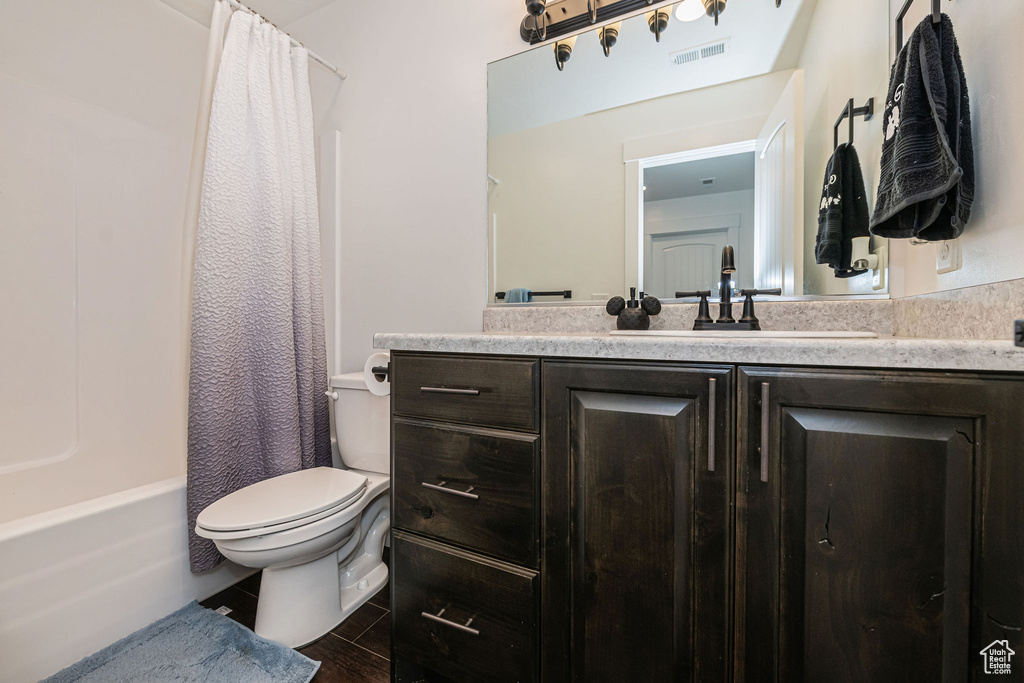 Full bathroom featuring shower / tub combo with curtain, vanity, and toilet