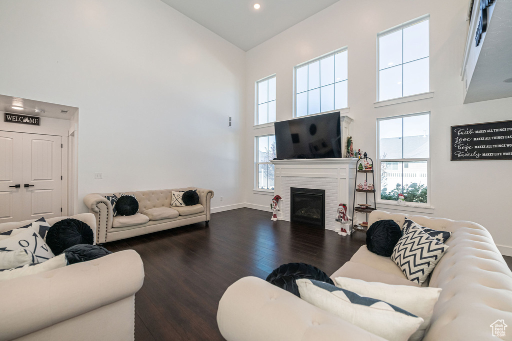 Living room featuring plenty of natural light, dark wood-type flooring, and a high ceiling