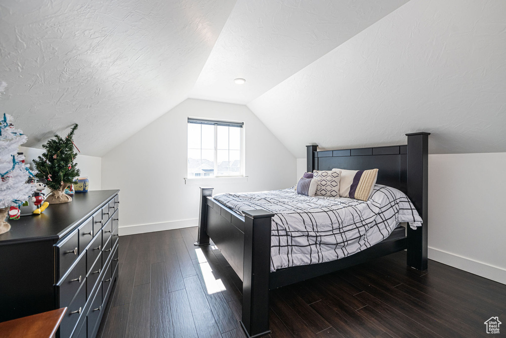 Bedroom with a textured ceiling, lofted ceiling, and dark hardwood / wood-style floors