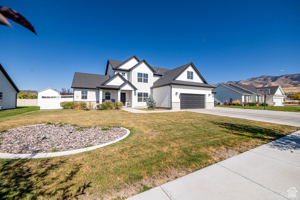 View of front of home with a mountain view, a garage, and a front lawn