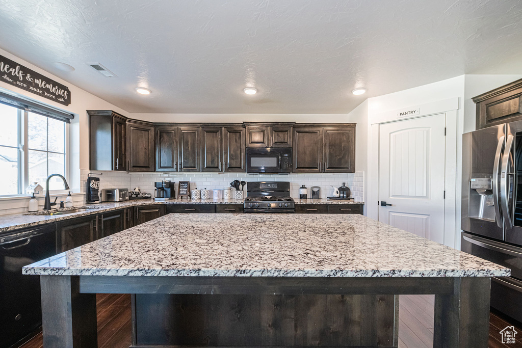 Kitchen with a kitchen island, sink, tasteful backsplash, and black appliances