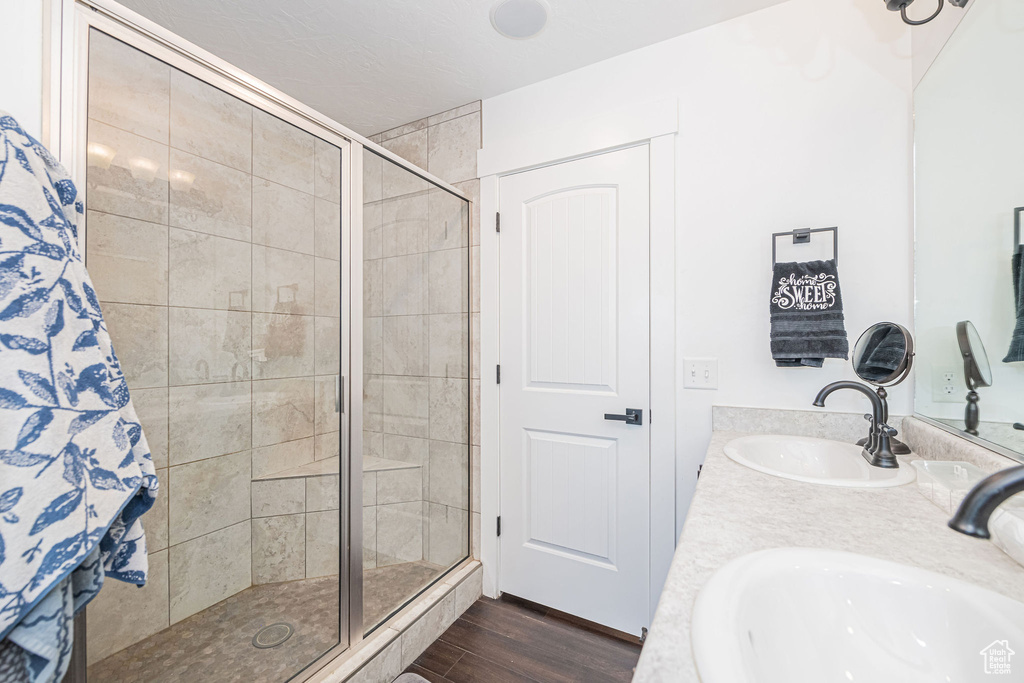 Bathroom with wood-type flooring, a shower with shower door, and vanity