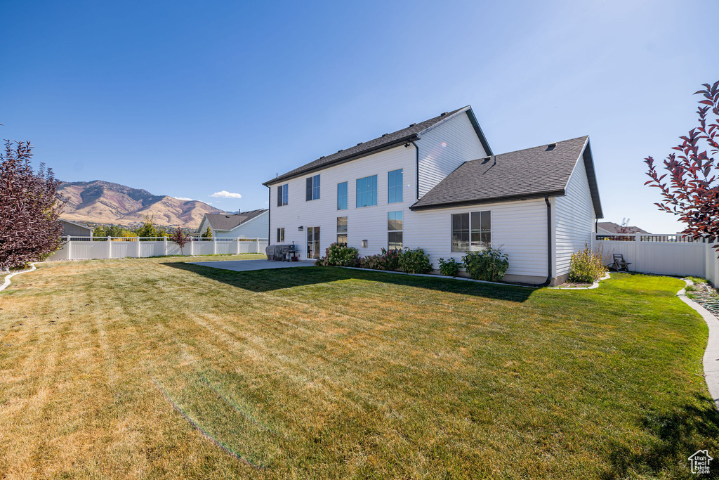 Rear view of property with a mountain view, a patio area, and a yard