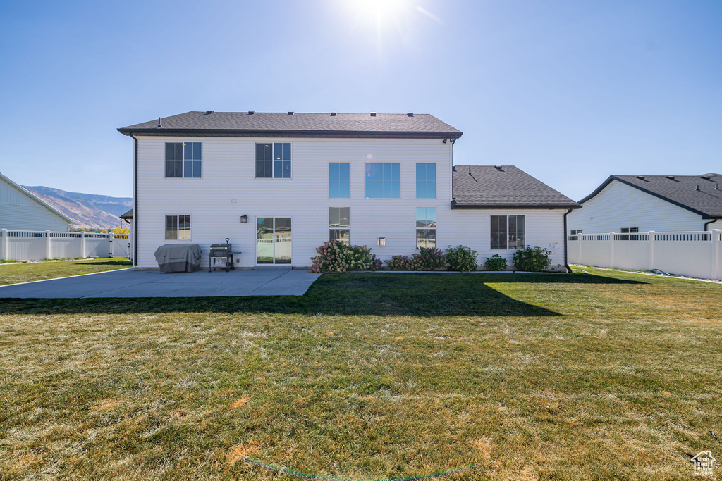 Rear view of house featuring a mountain view, a lawn, and a patio