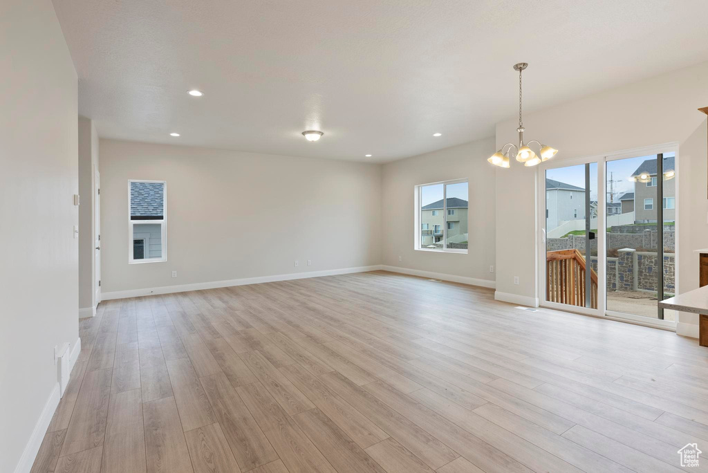 Unfurnished room featuring an inviting chandelier and light hardwood / wood-style floors