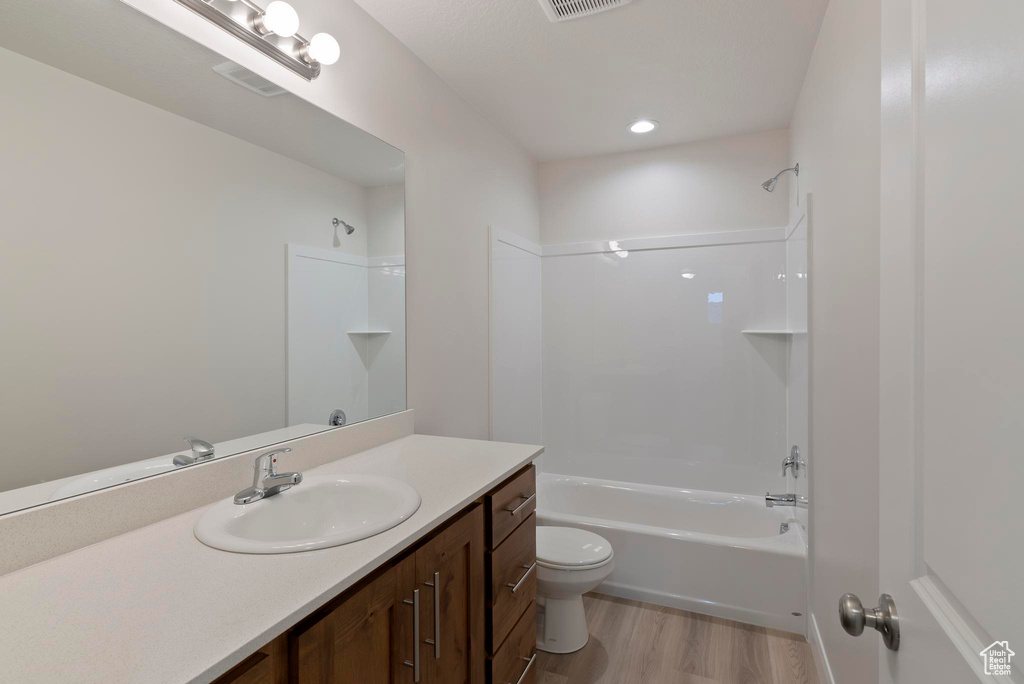 Full bathroom with shower / tub combination, vanity, hardwood / wood-style floors, and toilet