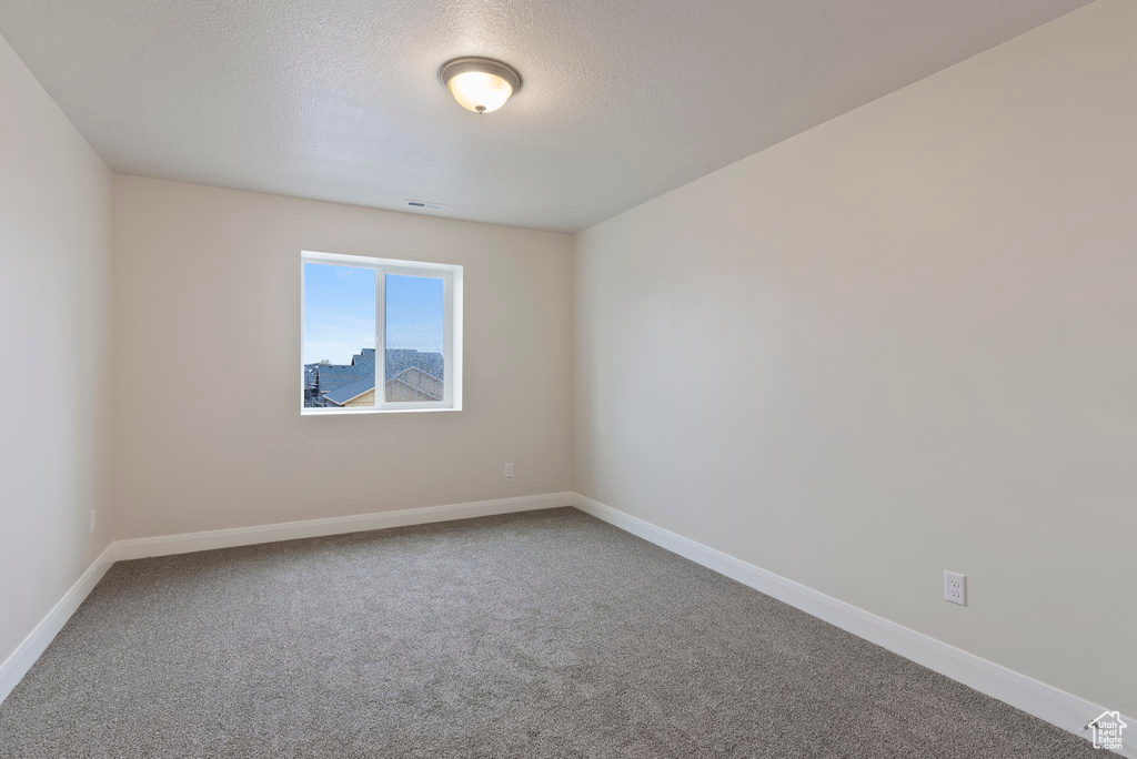 Spare room featuring a textured ceiling and carpet