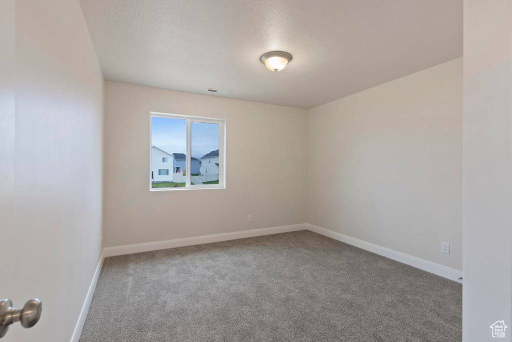 Unfurnished room featuring a textured ceiling and carpet flooring