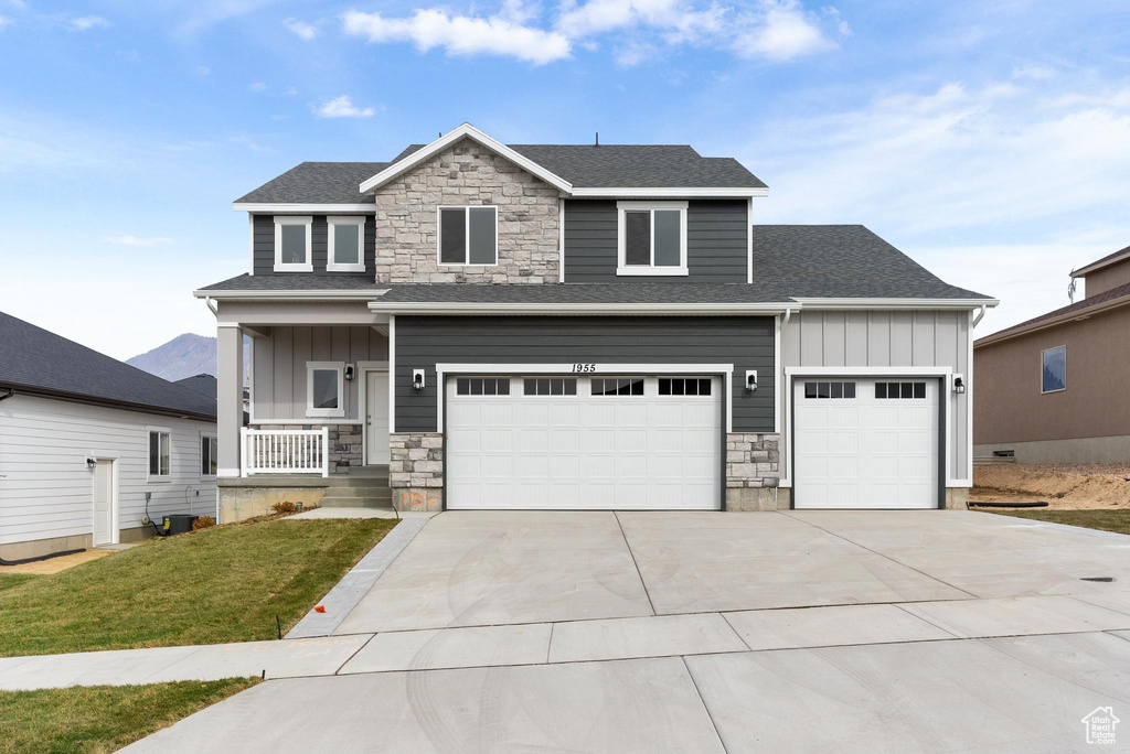 View of front of property featuring a garage, covered porch, and a front yard