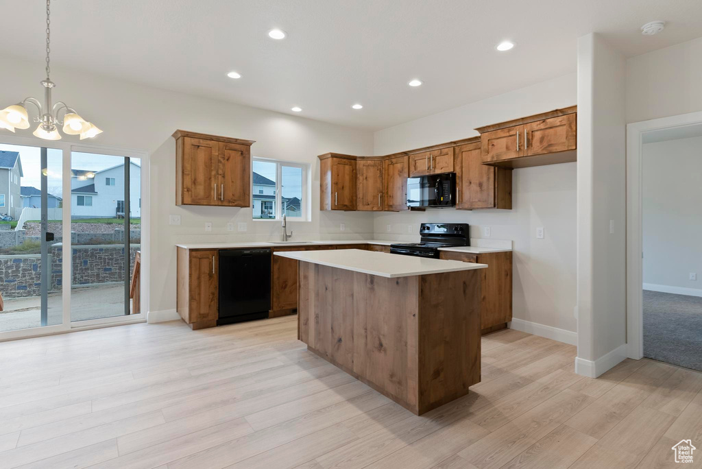 Kitchen featuring a chandelier, light hardwood / wood-style floors, a kitchen island, black appliances, and decorative light fixtures