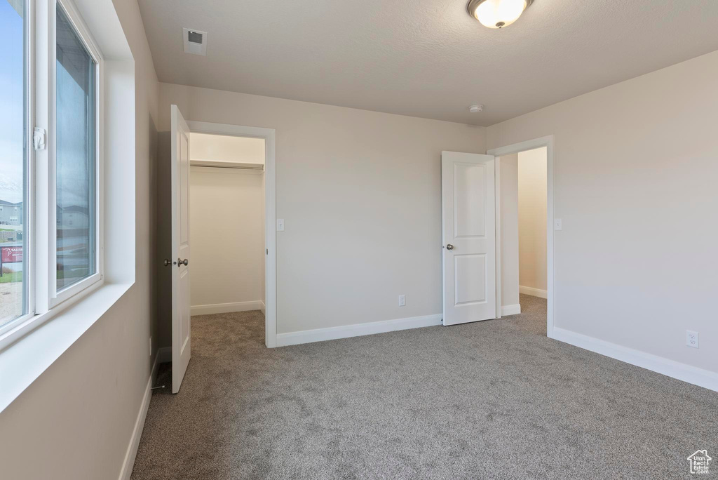 Unfurnished bedroom with carpet, a spacious closet, and a closet