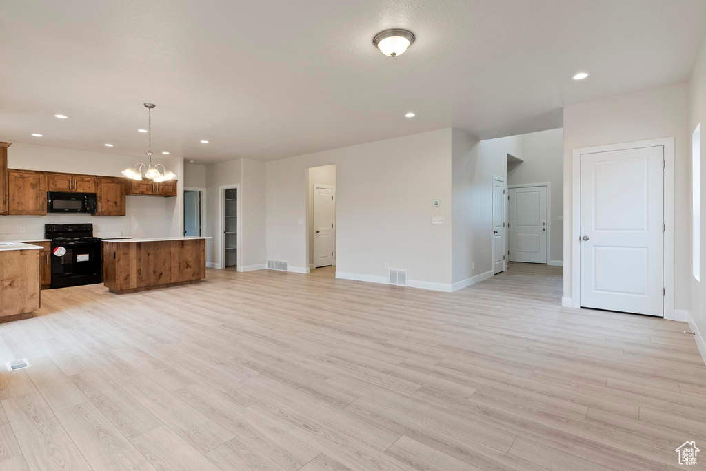 Kitchen featuring pendant lighting, a chandelier, black appliances, a center island, and light wood-type flooring