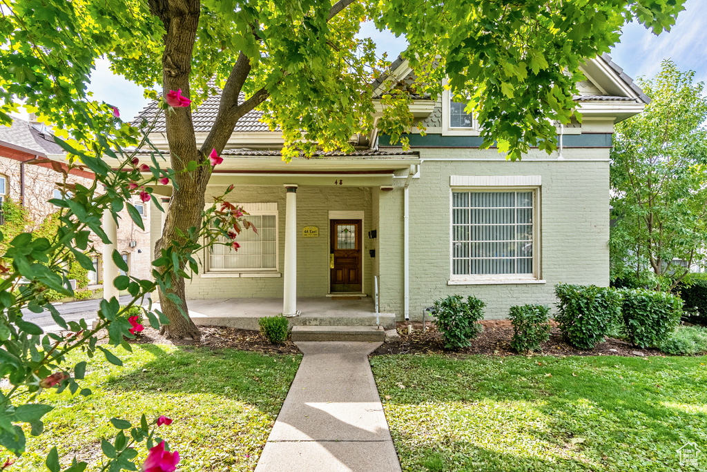 View of front facade featuring a front yard and covered porch