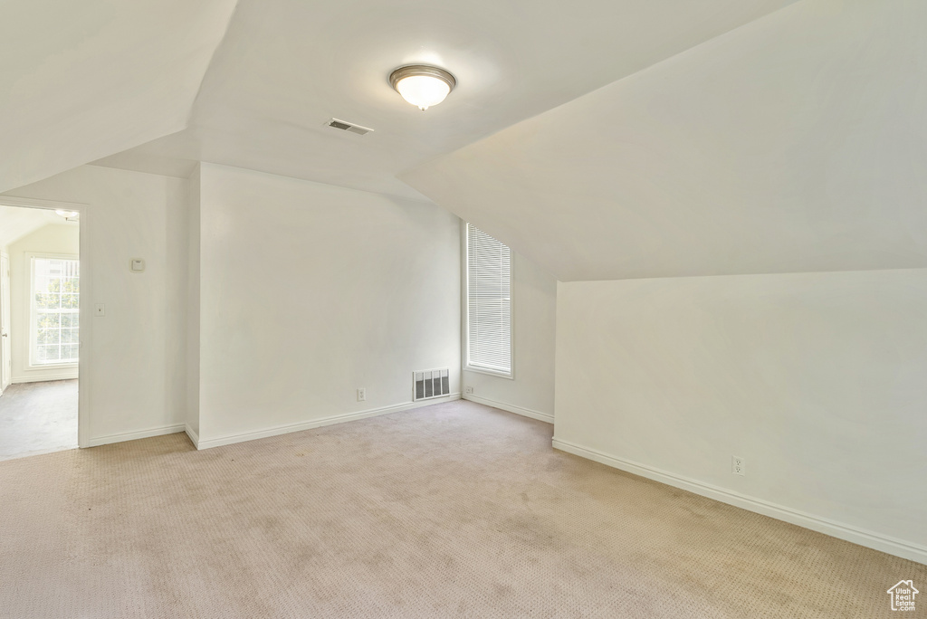 Bonus room with light colored carpet and lofted ceiling