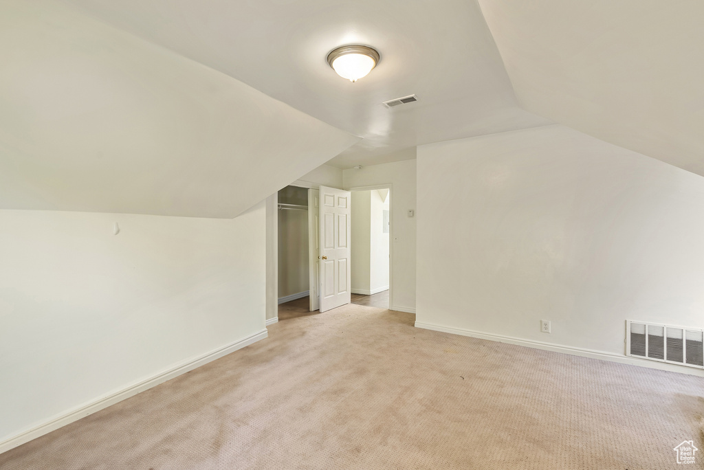 Additional living space with lofted ceiling and light colored carpet