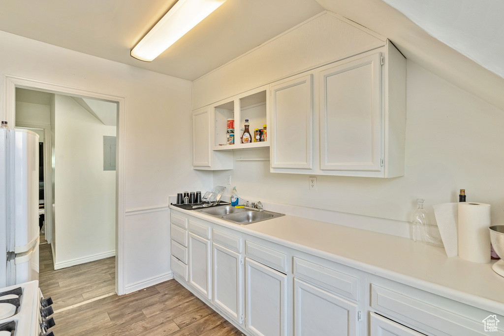 Kitchen featuring stove, light hardwood / wood-style flooring, sink, and white cabinets