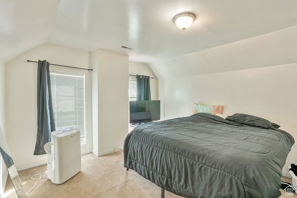 Bedroom featuring light carpet and vaulted ceiling