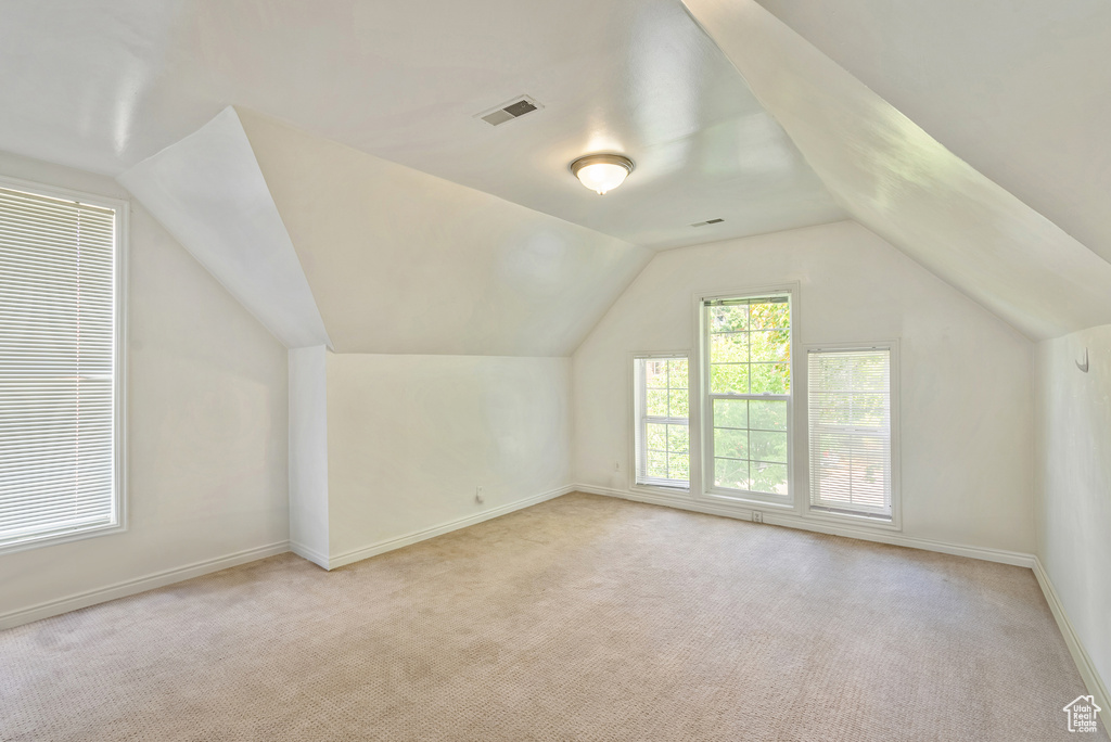 Bonus room with vaulted ceiling and light carpet