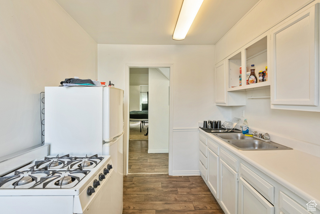 Kitchen featuring white cabinets, dark hardwood / wood-style floors, white range with gas cooktop, and sink