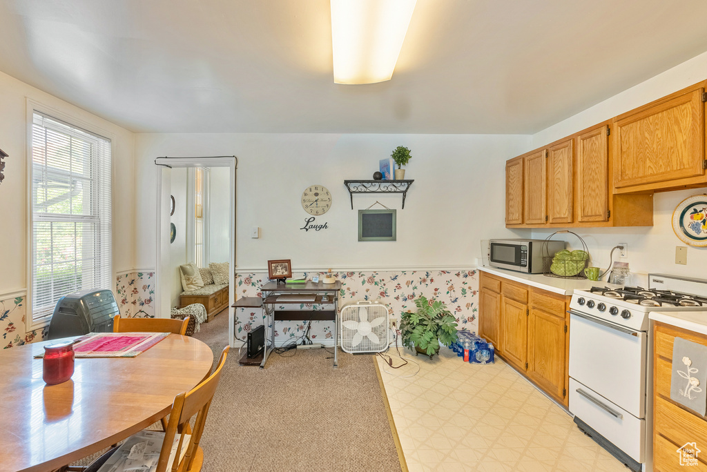 Kitchen featuring light colored carpet and white gas stove