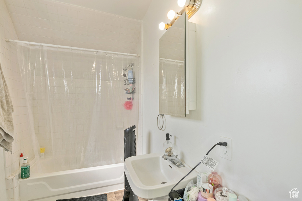 Bathroom featuring sink and shower / bathtub combination with curtain