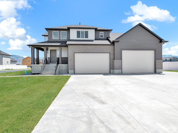 View of front of home with a garage, a front lawn, and covered porch