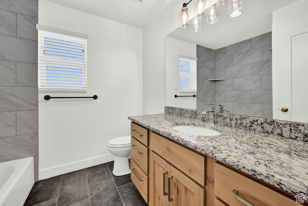 Full bathroom with tiled shower / bath, vanity, toilet, and tile patterned floors