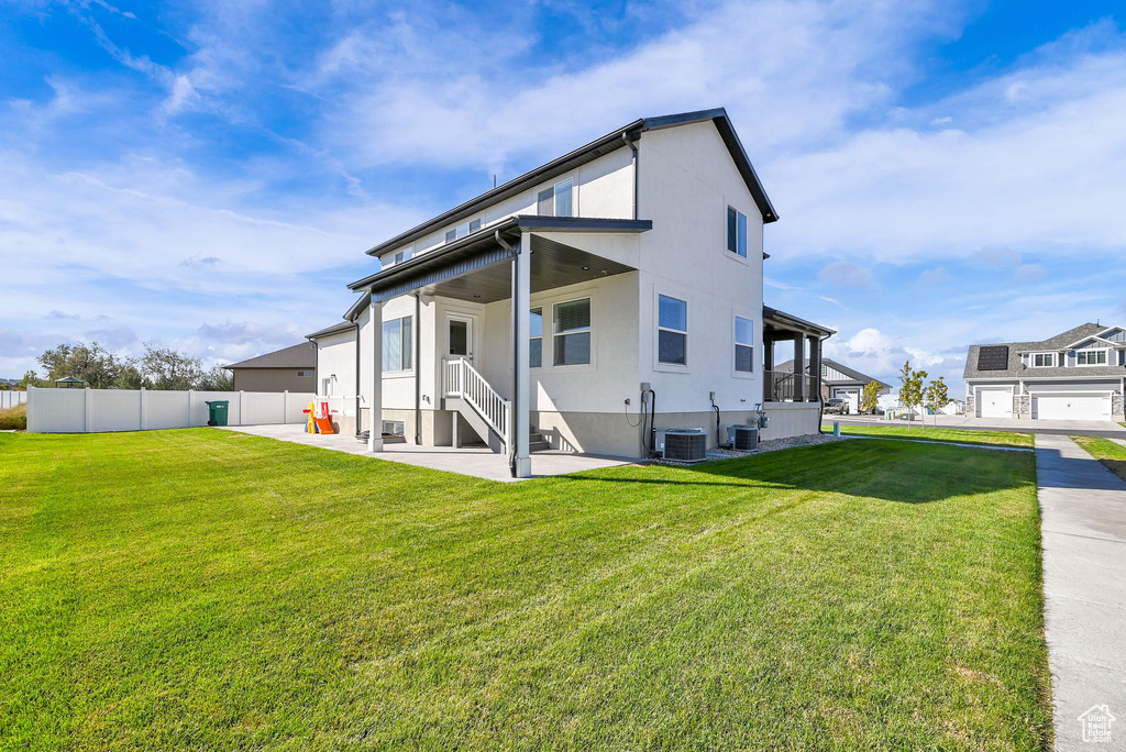 Rear view of house featuring a garage, a sunroom, a lawn, and central air condition unit