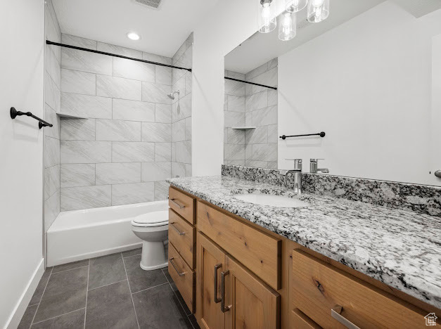 Full bathroom featuring vanity, tiled shower / bath combo, toilet, and tile patterned floors