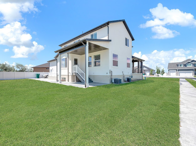 Rear view of house featuring cooling unit, a yard, and covered porch